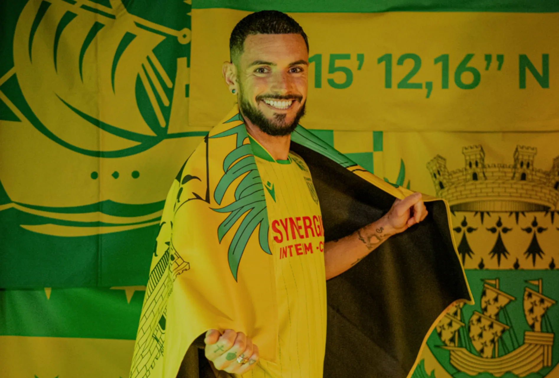 Rémy Cabella souriant avec le drapeau du FC Nantes